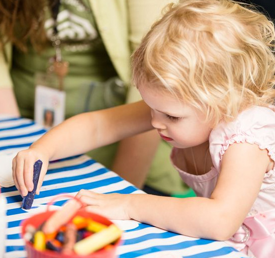 Child at SDCDM playing with crayons and drawing