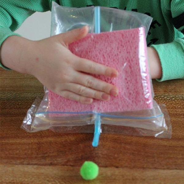 AirPressure Child holding a plastic bag with a straw and sponge to create air pressure in a bag.