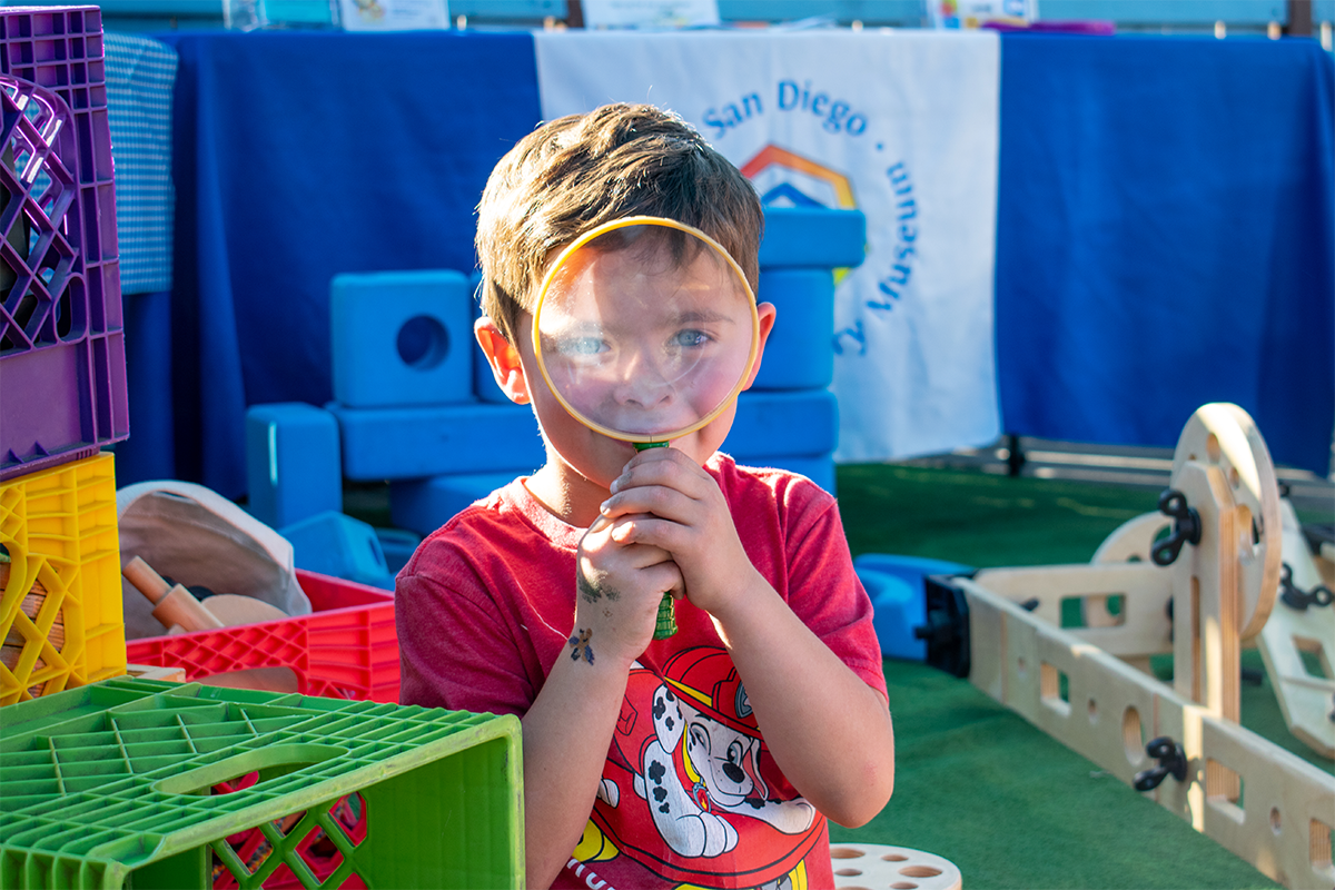 A little boy holding a magnifying glass up to his face