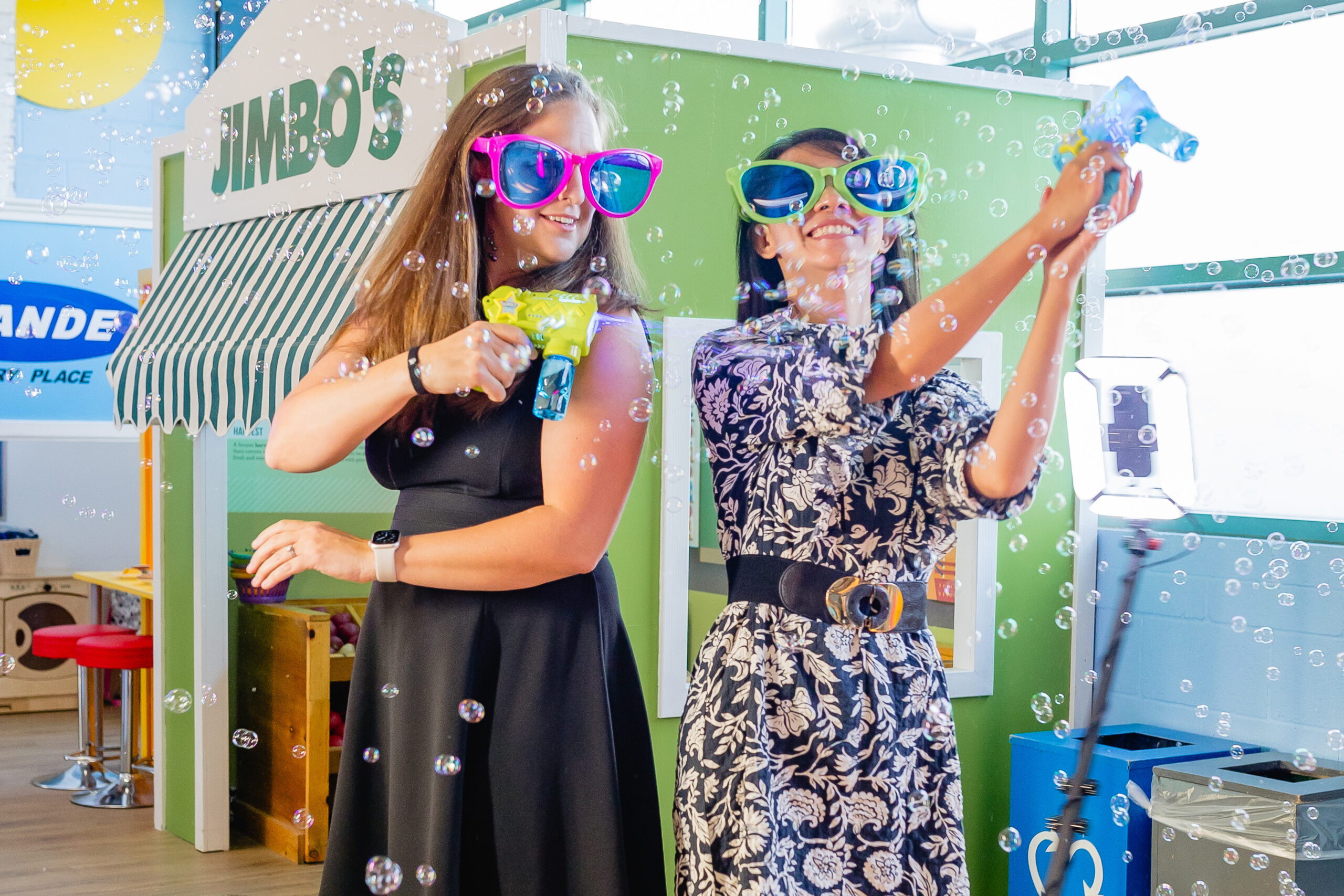 Two women with oversized sunglasses and bubble machines